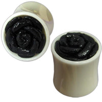 Load image into Gallery viewer, A pair of white bone plugs, hand-carved with a raised, glossy black leather flower design, shown from angled and top-down views. Product: Bone Plug weiß Leder Blume schwarz handgeschnitzt Tribal Organic Expander Tunnel Piercing.
