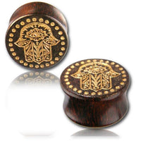 Cargar imagen en el visor de la galería, Two dark Holz Plug Poor Mans Hand Tamarind Khamsa plugs with gold-painted, laser-engraved Fatima eye and dotted tribal design, displayed on a reflective surface against a white background.
