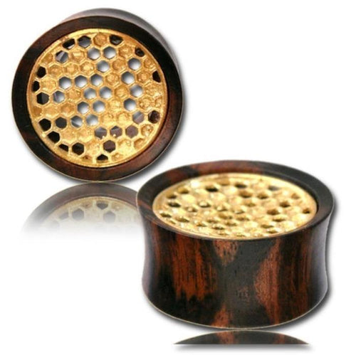 Two Holz Tunnel Tamarindenholz Waben Plugs feature antique gold brass inlays with a honeycomb design. One plug stands upright, the other lies flat, highlighting unique top and side views of this organic Tribal Plug Expander.