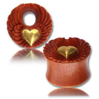 Cargar imagen en el visor de la galería, Two red-brown Sawo Holz Tunnel plugs feature antique gold brass heart and angel wing designs, nickel-free, with a tribal organic style, displayed on a white surface with a faint reflection.
