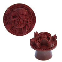 Load image into Gallery viewer, A round, rotbraun Holz Plug &quot;Pirat Totenkopf&quot; handgeschnitzt, double flared, features a raised skull with eye patch and headscarf over crossed bones, blending classic pirate motifs with artisanal woodwork.
