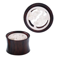 Load image into Gallery viewer, A pair of Holz Plug Tamarindenholz Tunnel Blumen Bone Inlay weiß Tribal Expander Ohrplug, made from dark brown tamarind wood with smooth, polished surfaces and intricate white bone floral inlays at the center.
