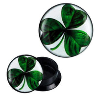 Load image into Gallery viewer, The Schraub Plug Acryl features a green three-leaf clover design on black under a glossy finish, displayed from two angles on a white background.
