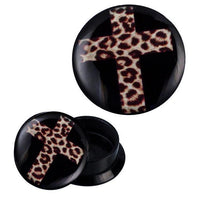 Load image into Gallery viewer, The Schraub Plug Acryl Kreuz Leoparden Design Piercing Ohrschmuck features black circular ear gauges with a leopard-print cross on the front; one is face up, the other open to show its hollow interior.
