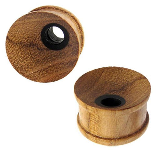Two Holz Tunnel Plug gemasert Loch klein, hand-carved from Teakholz and Eisenholz, with flared edges and a black center hole, are shown on a white background. One plug stands upright, the other is tilted to display front and side views.