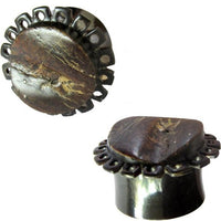 Load image into Gallery viewer, Two metal plugs with polished, dark brown horn tops featuring natural streaks and floral shapes, resembling the Horn Plug Blumenform dunkelbraun Rohhorn double flared, each with a shiny metallic cylindrical base.
