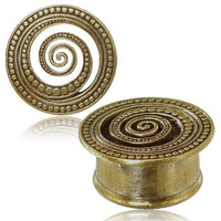 Load image into Gallery viewer, The Brass Tunnel Plug Spirale Punkte antik golden Messing Schmuck features two round plugs with a raised spiral and dotted pattern, one standing upright to show the golden design and one lying flat to display its cylindrical form.

