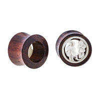 Load image into Gallery viewer, Two cylindrical Holz Plug Tamarindenholz Tunnel plugs—one upright, one on its side—display a hollow center decorated with white bone inlay floral patterns, highlighting the tribal artistry of these unique Expander Ohrplugs.
