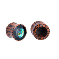 Load image into Gallery viewer, Two &quot;Holz Plug Tunnel Kokosholz&quot; ear gauges are shown on a white background: one features a shimmering Paua Abalone resin inlay with tribal circles, while the other reveals its hollow Kokosholz interior.
