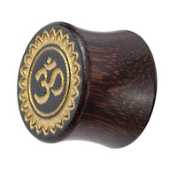 Cargar imagen en el visor de la galería, A hand-carved Tamarind wood plug with a flared shape, gold-painted Om design, and decorative laser-engraved border inspired by tribal organic Blume motifs.
