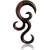 Load image into Gallery viewer, The Sonoholz lang hand-carved wooden spiral expander features an organic, abstract tribal-inspired design with flowing curves and pointed ends. Unisex ornament is presented on a white background with a subtle reflection below.
