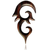 Load image into Gallery viewer, The Sonoholz lang Tribal Piercing features hand-carved, dark wood with pointed ornament and swirling curves. This unisex, organic expander displays a sharp, tribal-inspired design, shown against a white background.
