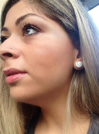Load image into Gallery viewer, A woman with long, light brown hair looks sideways, wearing a small nose piercing and round Ohstecker Shiva Auge 925 Silber earrings. She has long eyelashes and light pink lipstick.

