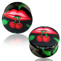 Load image into Gallery viewer, The Holz Plug Mund Kirschen rot schwarz Tunnel Unisex Ohrschmuck Teakholz features black circular plugs with red lips holding cherries by the stems, accented by green leaves for a striking and playful ear accessory.
