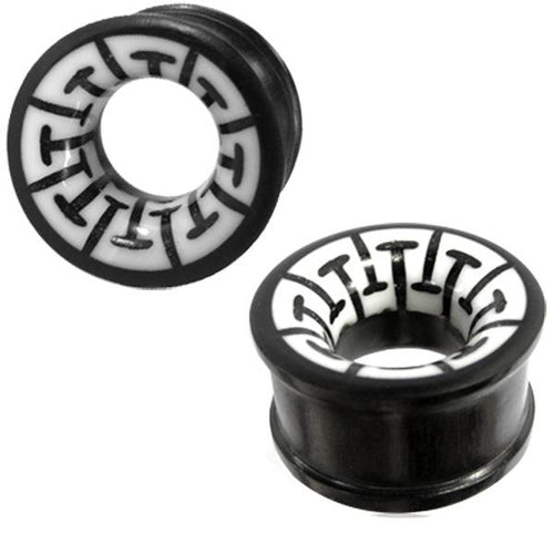 Two black "Tribal Holz Tunnel" ear plugs, hand-carved from ironwood with white bone inlays featuring a geometric black pattern. These cylindrical plugs blend modern style with traditional design.