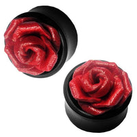 Load image into Gallery viewer, Two black circular Leder Holz Plugs by Sonoholz feature a raised red rose design with sculpted petals. These unisex tribal tunnel ear plugs add an elegant, artistic touch to any look.
