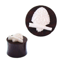 Load image into Gallery viewer, The Sonoholz Plug Bone Inlay Tribal Expander features a white, intricately carved owl on a branch atop a round, dark brown surface, shown from both side and top-down views.
