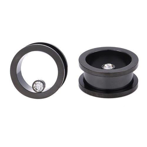 Zwei schwarze Edelstahl Flesh Tunnel ribbed Plugs mit Glitzer-Zirkonia Stein: Einer steht aufrecht und zeigt den hohlen Kern, der andere liegt flach und präsentiert den funkelnden Stein am Rand.