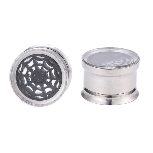 A pair of Chirurgenstahl Plug silber Farben, one displaying a black Spinnennetz motiv under glass, the other shown from the side—both are thin, screw-fit plugs crafted from shiny surgical steel.