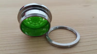 Load image into Gallery viewer, The Schraubplug Chirurgenstahl Tunnel Edelstahl silber features a neon green Spinnennetz acrylic design, shown partially open with the threaded ring next to it on a light wooden surface.
