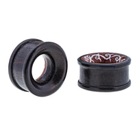 Load image into Gallery viewer, Two Holz Tunnel Bone Inlay Kranz Spiralen Tribal Plugs from Sonoholz Tamarindenholz are shown—one upright showing the hollow center, the other on its side revealing a handgeschnitzt white inlay pattern.

