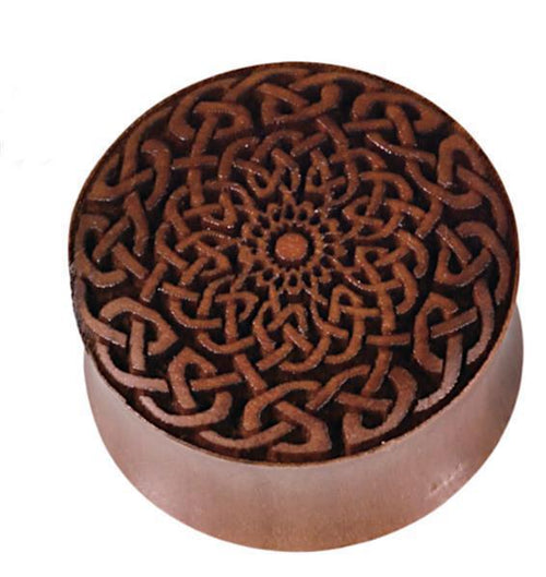 A round brown wooden box, "Plug Celtic Sawoholz," features a laser-engraved braided Celtic design on its lid with a symmetrical floral motif, echoing the style of a hand-carved Holzplug.