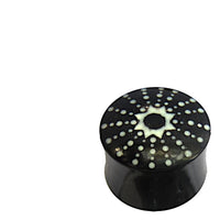 Cargar imagen en el visor de la galería, The Horn Plug schwarz weiß Stern Punkte handgeschnitzt is a hand-carved double flared plug from buffalo horn, featuring a black cylindrical shape with a white sunburst and dot pattern on top, shown on a white background.

