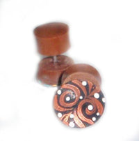 Load image into Gallery viewer, Two round, brown Tribal Fake Plug Holz Edelstahl Tunnels (1 mm), one showing a hand-painted front with black swirls and white dots, the other upright. Both are made of curved Sonoholz. Background is plain white.
