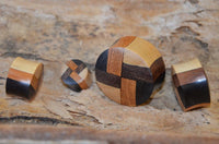 Load image into Gallery viewer, Four &quot;laminiert Holzplug vier Farben Muster Tribal Holz Plug&quot; in various shapes and wood patterns are arranged on a textured wooden surface, with the largest piece being round and others smaller, featuring dark and light wood designs.
