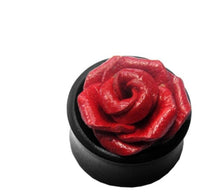 Load image into Gallery viewer, A round black &quot;Leder Holz Plug schwarz Sonoholz&quot; features a detailed, sculpted red rose design on top—ideal as unisex tribal tunnel lobe jewelry. Shown against a white background.
