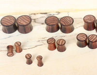Load image into Gallery viewer, Holz Plug Sonoholz Zebraholz Inlay gestreift Tunnel Tribal Expander Ohrplug in various sizes are arranged on a light wooden surface, each featuring a dark finish with striped grain patterns on top.
